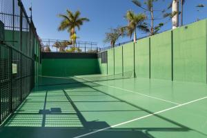 a tennis court with palm trees in the background at Sunset Villa Meloneras in Maspalomas