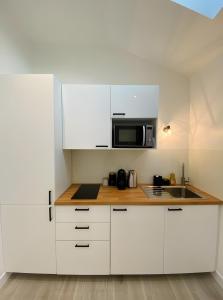 a kitchen with white cabinets and a microwave at La Folie Romantique, Avec Spa in Sublaines