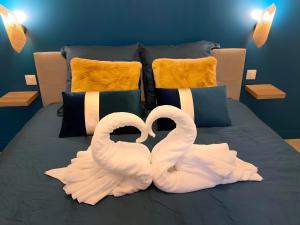 two white swans sitting on top of a bed at La Folie Romantique, Avec Spa in Sublaines +2 photos