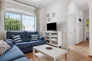 a living room with a blue couch and a tv at Chalet Fuente3 piscina común famila in Conil de la Frontera