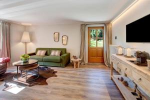 a living room with a green couch and a tv at Chalet Sonne - Livigno in Livigno
