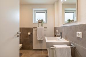 a bathroom with a sink and a toilet and a mirror at Fewo Parkside S4 - 8Min Legoland in Günzburg +19 photos
