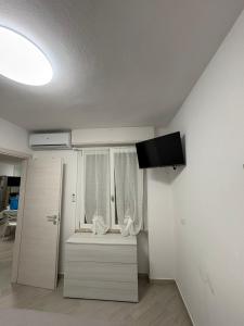 a white room with a window and a television at Appartamenti Flora in Castelsardo