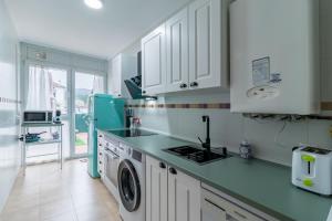 a kitchen with white cabinets and a washer and dryer at Surf House Gama in Gama