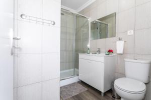 a white bathroom with a toilet and a shower at Oásis Fonte Grande in Santo António +37 photos