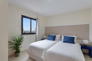 a bedroom with a large white bed with blue pillows at Luxury Ático Plaza in Playa de San Juan