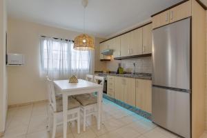 a kitchen with a white table and a refrigerator at Luxury Ático Plaza in Playa de San Juan