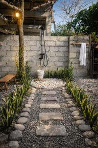a garden with a stone walkway next to a wall at The Stoked Hideout - Bagasbas Beach in Daet