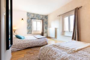 a bedroom with two beds and two windows at La ferme du château in Venon