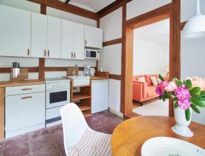 a kitchen with white cabinets and a table with a vase of flowers at Künstlerwohnung im Naturpark in Meezen +4 photos