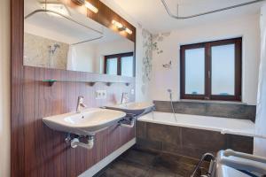 a bathroom with two sinks and a tub and a mirror at Freiraum in Weiler-Simmerberg