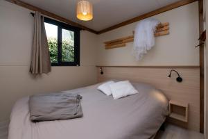 a bedroom with a large white bed and a window at Chalet 20m2 - Ile Vierge in Plouhinec