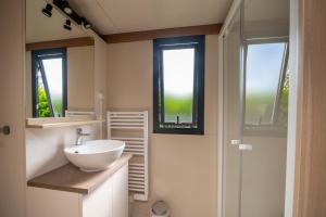 a bathroom with a white sink and two windows at Chalet 20m2 - Ile Vierge in Plouhinec +13 photos