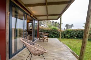 a wicker chair sitting on the porch of a house at Chalet 20m2 - Ile Vierge in Plouhinec