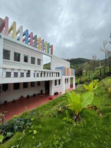 a large white building with a grassy field in front of it at Green Valley in Kolakambe