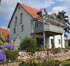 a house with a balcony on top of a stone wall at Ferienwohnung Walter in Ellenbach