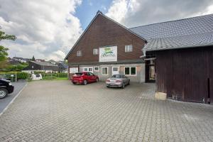 a building with two cars parked in a parking lot at Ferienwohnung auf dem Ennerthof in Arnsberg