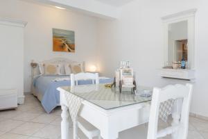 a white bedroom with a bed and a table and chairs at Caldera Studios in Astypalaia +43 photos