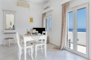 a white dining room with a white table and chairs at Caldera Studios in Astypalaia