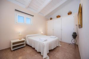 a white bedroom with a white bed and a window at Can Claret in Felanitx