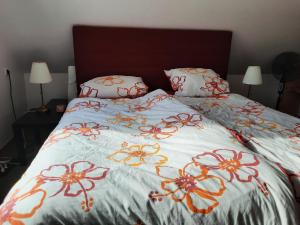 a bed with an orange and white blanket and pillows at Yachthof Ferienwohnung, 60 m² in Scheid +2 photos