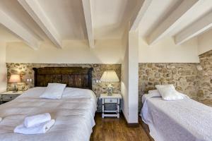 two beds in a room with stone walls at Grans Paisatges in Orriols