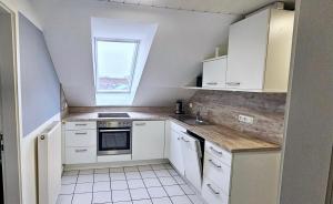 a small kitchen with white cabinets and a window at Büsummchen in Büsum