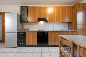 a kitchen with wooden cabinets and a white refrigerator at Casa Colonia 1 in SantʼAnna Arresi