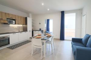 a kitchen and living room with a table and a blue couch at Holiday home Galatea a Otranto in Otranto