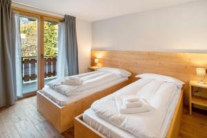 two twin beds in a room with a window at Quattropassi Bormio Mortirolo in Bormio