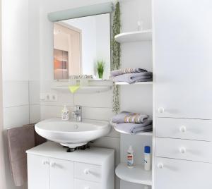 a white bathroom with a sink and a mirror at Ferienwohnung Am Palmengarten in Marktbergel +18 photos