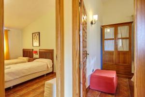a bedroom with two beds and a red stool at La Aldeilla in Aldeaquemada +154 photos
