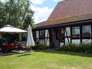 a house with an umbrella and a table and chairs at Maison Fleurie in Mitschdorf