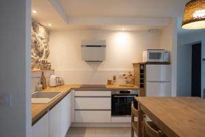 a kitchen with white appliances and a wooden table at Appartement de charme - La Tour in La Tour