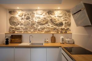 a kitchen with a stone wall in the background at Appartement de charme - La Tour in La Tour +9 photos