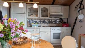 a kitchen with white cabinets and a wooden table with flowers at Kleines Quickborn in Quickborn