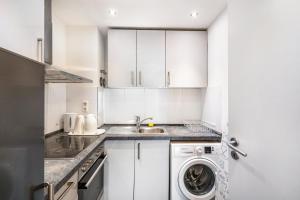 a kitchen with white cabinets and a washer and dryer at Aldars Urban Suite No.10 in Munich