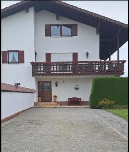 a white house with a balcony and a driveway at Ferienwohnungen Landhaus Strell in Bad Griesbach