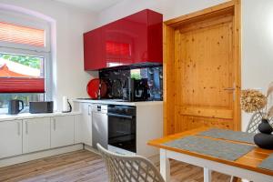a kitchen with red cabinets and a table with chairs at Ferienhaus Dorfidyll in Bugewitz