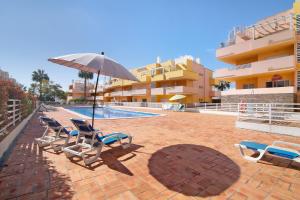 a group of chairs and an umbrella next to a swimming pool at Apartamento Royal Cabanas Golf in Conceição