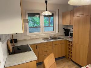 a kitchen with wooden cabinets and a sink and two windows at Ferienwohnung Ingrid Rautenberg in Krautheim +10 photos