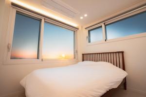 a bedroom with two windows and a white bed at 포항 이가리 독채 풀빌라 엘리시안 풀빌라펜션 in Pohang +7 photos