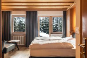 a bedroom with a large bed and two windows at La Grambla App Saslonch 1 in Santa Cristina Gherdëina