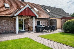 a patio with a table and chairs in front of a building at Dat Haddehuus in Wangerland