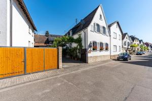 a street with white houses and a yellow fence at Gästehaus Gross in Neustadt an der Weinstraße