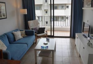 a living room with a blue couch and a table at Sunny apartment with pool in Tossa de Mar