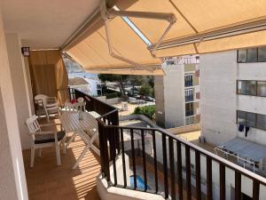 a balcony with a table and umbrella on a building at Sunny apartment with pool in Tossa de Mar