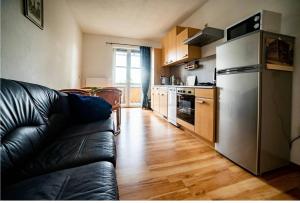 a kitchen with a stainless steel refrigerator and a black leather couch at Moderne Ferienwohnung in der Stadt in Forst