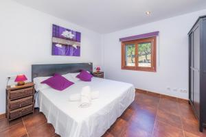 a bedroom with a large white bed with purple pillows at Finca Bionic in Artá +36 photos