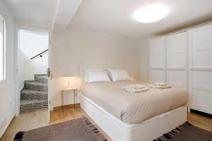 a white bedroom with a bed and a staircase at Casa Do Lenhador in Canhas
